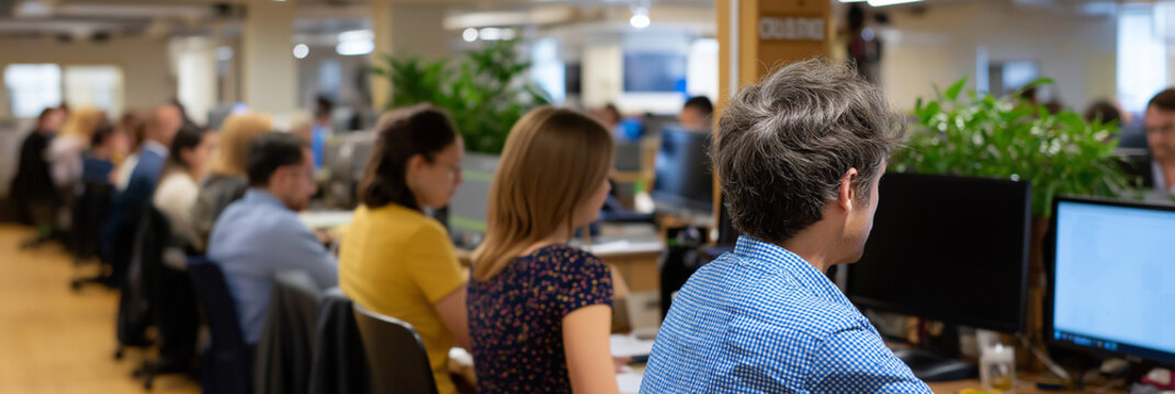 A vibrant open office environment filled with focused employees working diligently at their computers, showcasing modern workspace design and collaborative dynamics.