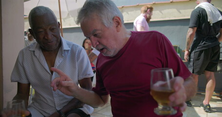 Two elderly friends sharing a meaningful conversation over drinks at a backyard barbecue,...