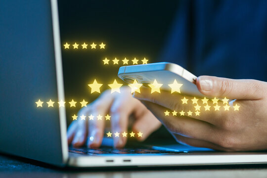 Person using a smartphone while typing on a laptop with glowing star ratings in the background