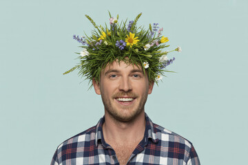 A cheerful smiling man with grass and flowers on his head.