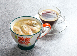 Enjoy a soothing moment with wonton soup and coffee. The warm soup and aromatic coffee create a delightful, comforting experience for a cozy day.