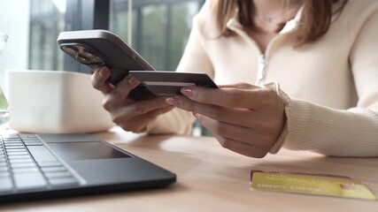 Close-up of a woman using a smartphone and holding a credit card for online shopping or payment, symbolizing digital finance and modern lifestyle. - Powered by Adobe