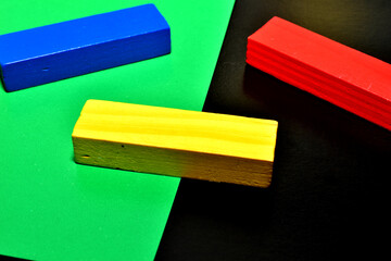 Three wooden blocks of the Jenga board game, painted blue, yellow and red.