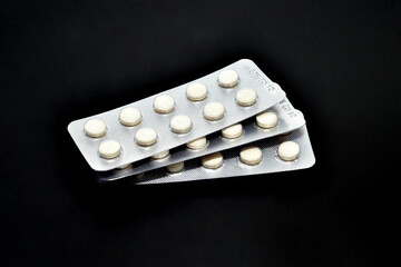 A stack of pills in packaging on a black background.