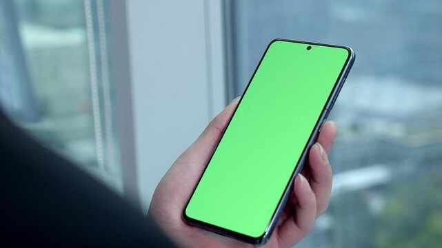Holding a mobile phone with a green screen, you can change the video template on the phone screen