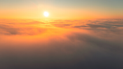 Golden evening light shining over fog filled Bavarian valleys captured from above in a scenic aerial landscape