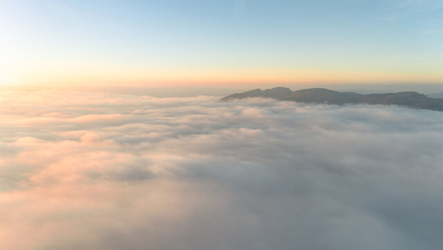 Aerial drone shot of fog blanket glowing in the warm evening sun over calm Bavarian countryside