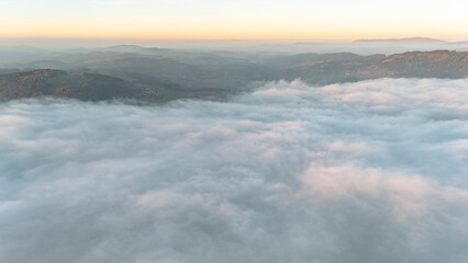 Aerial drone landscape with golden evening sun over fog in Bavaria showing calm hills forests and valleys