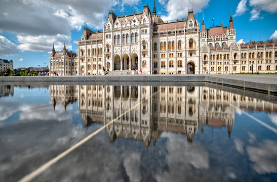 Budapest, Hungary - July 27, 2025: Reflection of the Hungarian Parliament Building in the shallow pool at Kossuth Lajos Square under a dramatic summer sky
