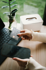Close-up of a woman using a smartphone and holding a credit card for online shopping or payment, symbolizing digital finance and modern lifestyle.