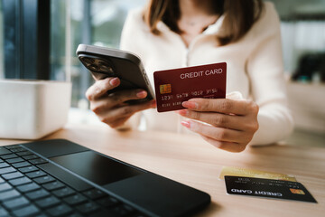 Close-up of a woman using a smartphone and holding a credit card for online shopping or payment, symbolizing digital finance and modern lifestyle.