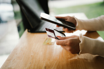 Close-up of a woman using a smartphone and holding a credit card for online shopping or payment, symbolizing digital finance and modern lifestyle.