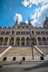 Fototapeta premium Budapest, Hungary - July 27, 2025: Exterior view of the Hungarian Parliament Building showcasing Neo-Gothic architecture and intricate stonework under a dramatic sky 