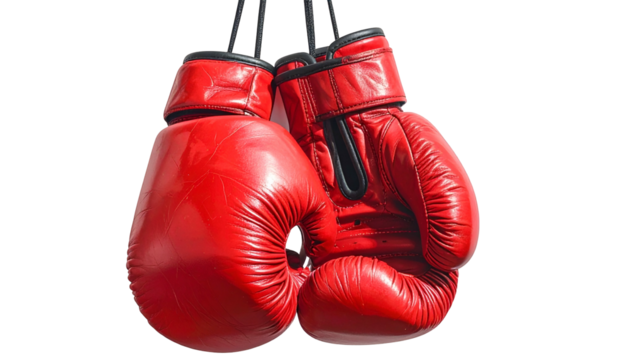 Pair of bright red boxing gloves, hanging by their laces, against a clean black background