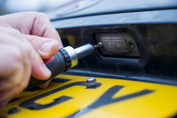 Unscrewing the screw from car light bulb, replacing the old light with a new one