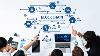 A team of professionals collaborates on blockchain technology, showcasing various components including security and tokenization through laptop displays and printed reports. Amity