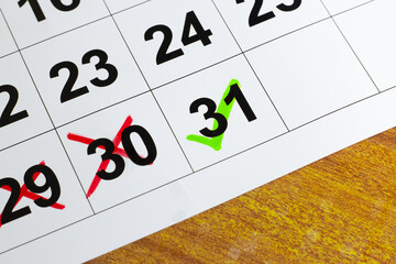 Calendar on the table with 29 30 mark crossed in red color and 31 in green color tick representing important date to remember. Due date reminder