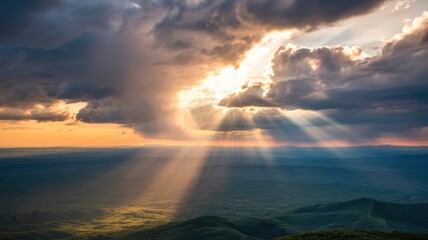 Golden sunlight pierces dramatic clouds, casting ethereal rays over a vast, lush mountain landscape during a breathtaking sunset.