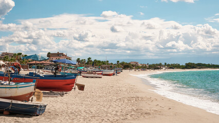 Colorful fishing boats on the sandy beach of Marina di Nicotera, Calabria, Italy, under a bright summer sky. Peaceful coastal scenery and Mediterranean holiday atmosphere.