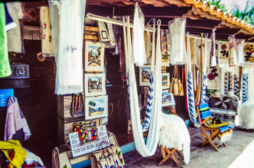 Daytime view of a Mexican tourist stall with fabrics and artwork.