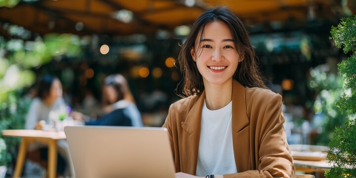 Portrait of smiling Asian executive working outdoors with laptop on sunny day, concept for business presentation, remote collaboration and flexible workspace