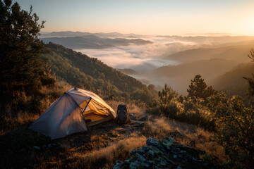 Scenic mountain campsite at sunrise with a view of fog-covered valleys and hills
