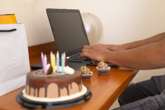 Man working on laptop beside a decorated birthday setup, concept of remote work-life balance and digital lifestyle.
