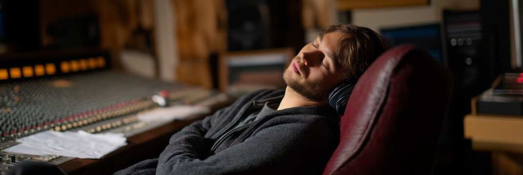 A sound engineer peacefully sleeps in a recording studio, highlighting the demanding nature of creativity and the need for rest to recharge artistic inspiration and innovation.