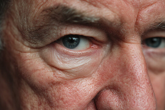 Close-up of elderly man's face highlighting detailed blue eyes and skin texture