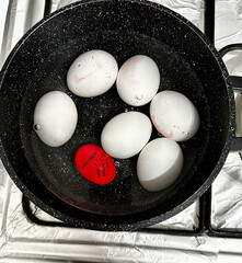 Boiling eggs in a pot with a doneness indicator. Kitchen cooking process, top view.