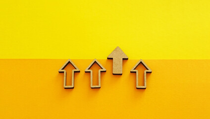 Wooden arrows pointing up on yellow background - business growth, leadership and competitive advantage concept