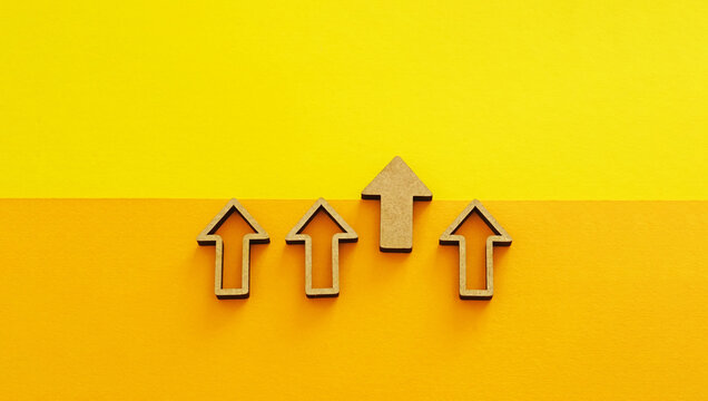 Wooden arrows pointing up on yellow background - business growth, leadership and competitive advantage concept