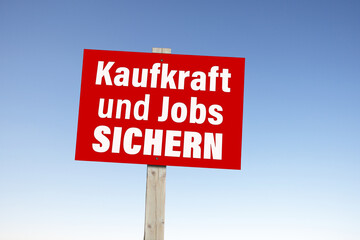 Kartonschild mit der Devise: Kaufkraft und Jobs sichern
