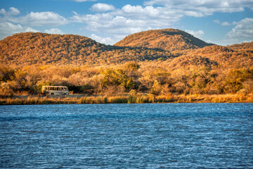 lake, dam at Mokolodi Nature Reserve, bus with tourist in game drive in natural african reserve , hill range, located near Gaborone, Botswana