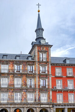 The highly decorated facade of Madrid's Casa de la Panader&iacute;a on the Plaza Mayor, featuring vibrant frescoes, two ornate towers, multiple balconies, and flags flying