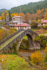 Vertical View of the Historic Stone Bridge and Traditional Houses of Vovousa Village, Pindos, Greece, During a Colorful Autumn Day