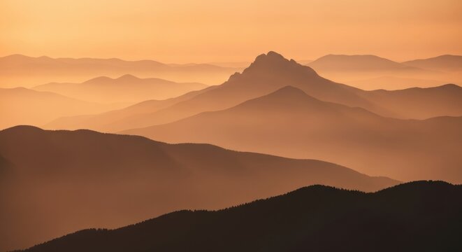Misty mountain range silhouette at golden hour. Layered hills creating depth and perspective. Warm orange glow over a vast wilderness landscape. Abstract nature for inspiration