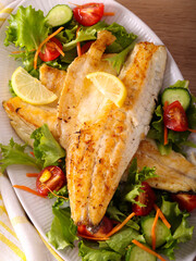 Fried seabass fillet with salad on plate