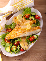 Fried seabass fillet with salad on plate