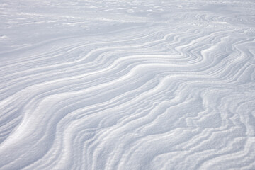 Snow waves on a frozen river. A whimsical natural pattern.