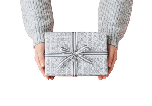 Hands holding a gift box wrapped in silver paper with a ribbon, isolated on transparent background
