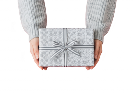 Hands holding a gift box wrapped in silver paper with a ribbon, isolated on transparent background