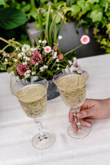 There are two glasses of champagne on the table in an evening setting.