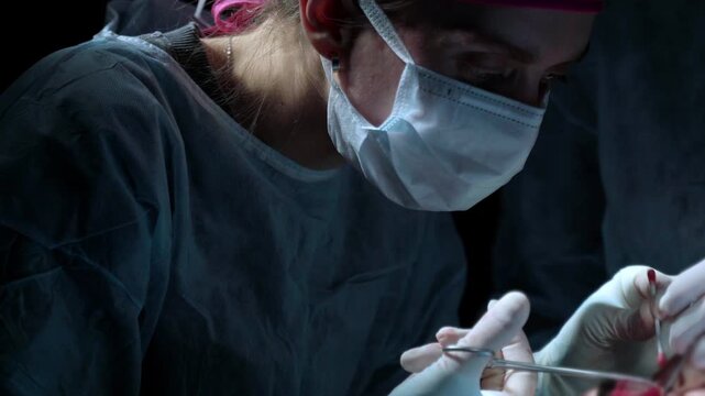 Female surgeon in a sterile operating room performing a complex medical procedure with precision and concentration, using surgical instruments to save a patient's life in a hospital - Powered by Adobe