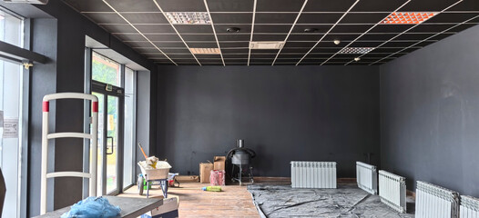 Empty interior of a commercial space in transition with black walls and heating units