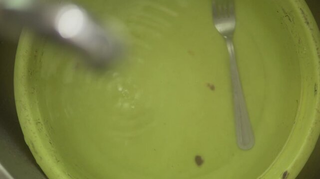 Water dripping into a green basin creating ripples