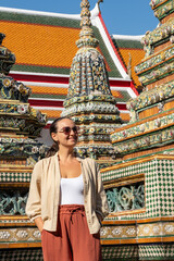 Smiling woman posing near ornate temple structure under sunlight, symbolizing travel joy and cultural exploration concept