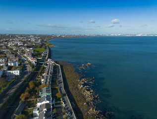 Drone shot of the historic blackrock area in dublin, showing the residential houses, coast and dublin bay with the mountains in the distance