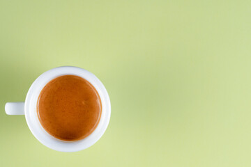 A top view of double espresso in white cup on green background