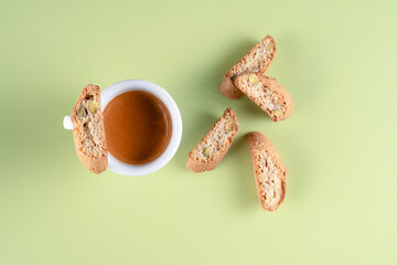 A cup of strong espresso paired with crunchy Italian cantucci cookies containing pistachios, perfect for a delightful coffee moment